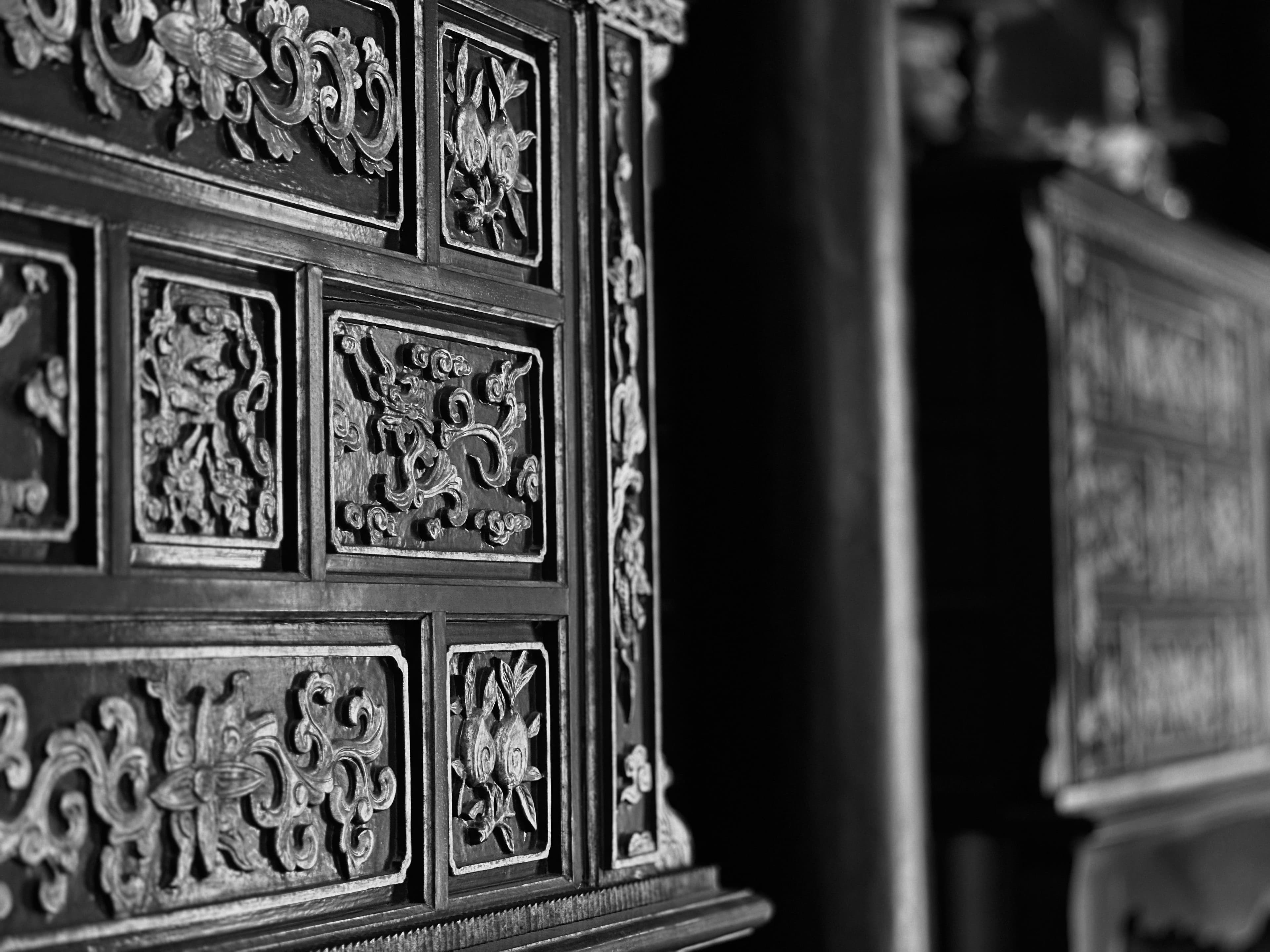Carved wooden panels in close-up, floral and cloud relief picked out by low side light