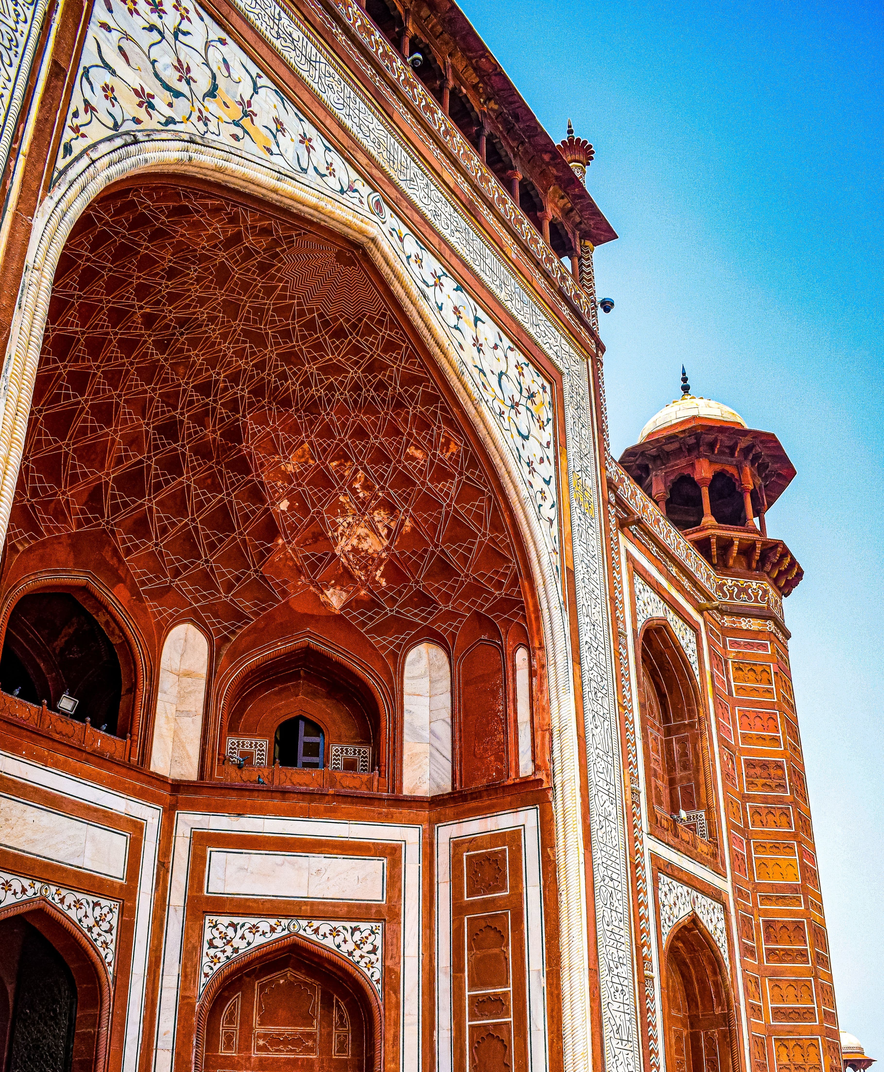 The red sandstone gateway at Sikandra, Agra, inlaid with white marble geometry against a hard blue sky