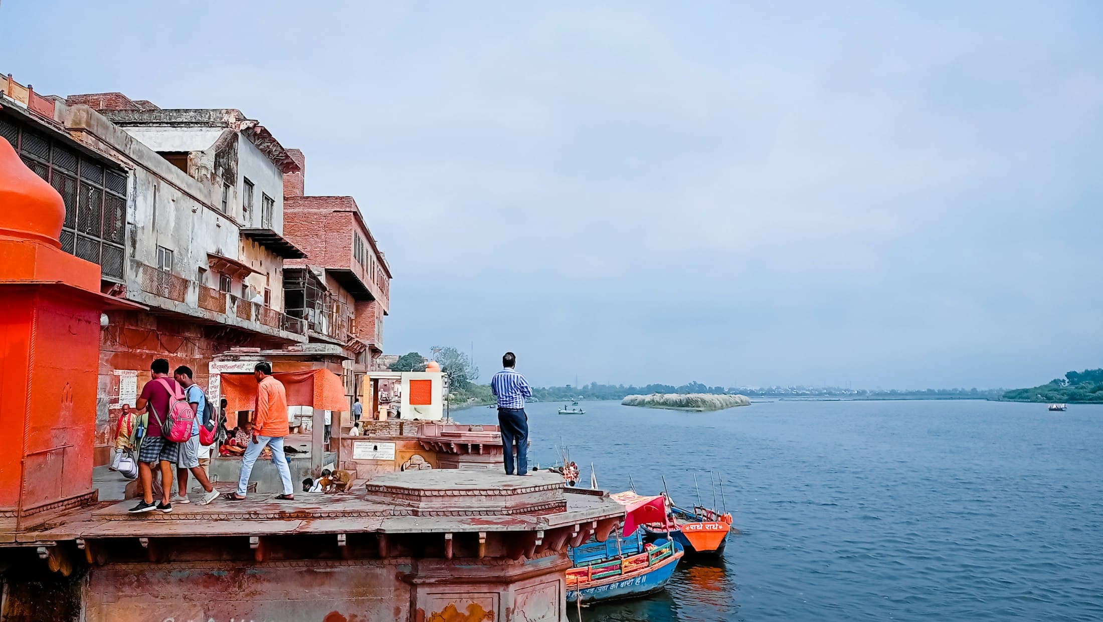 Boats moored at a ghat, the river opening out beyond the painted buildings