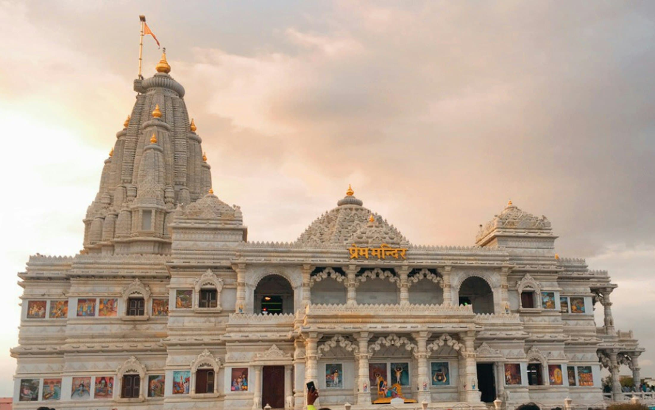 A carved temple front lit against a dusty evening sky