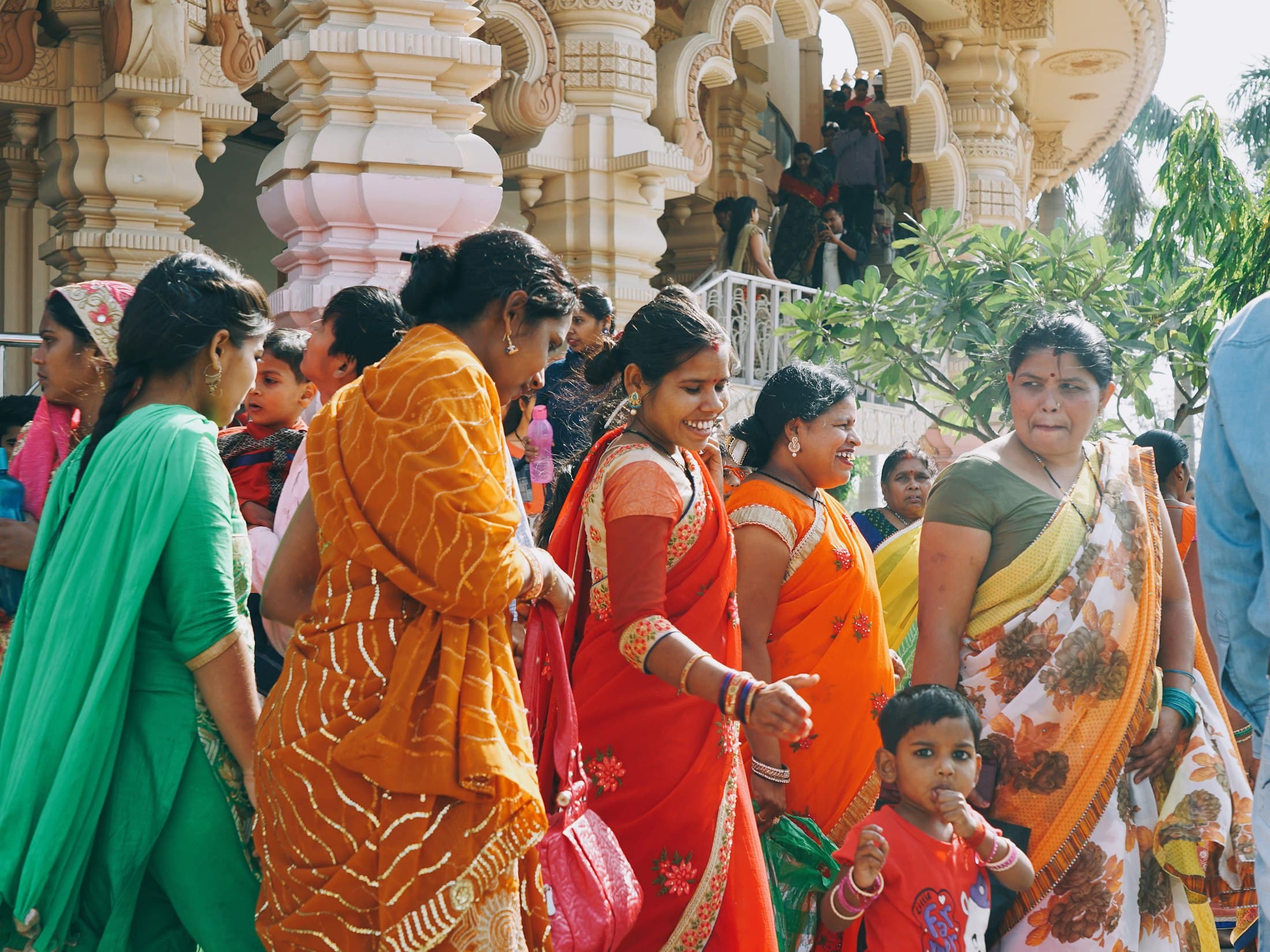 Women in bright saris gathered between carved temple pillars