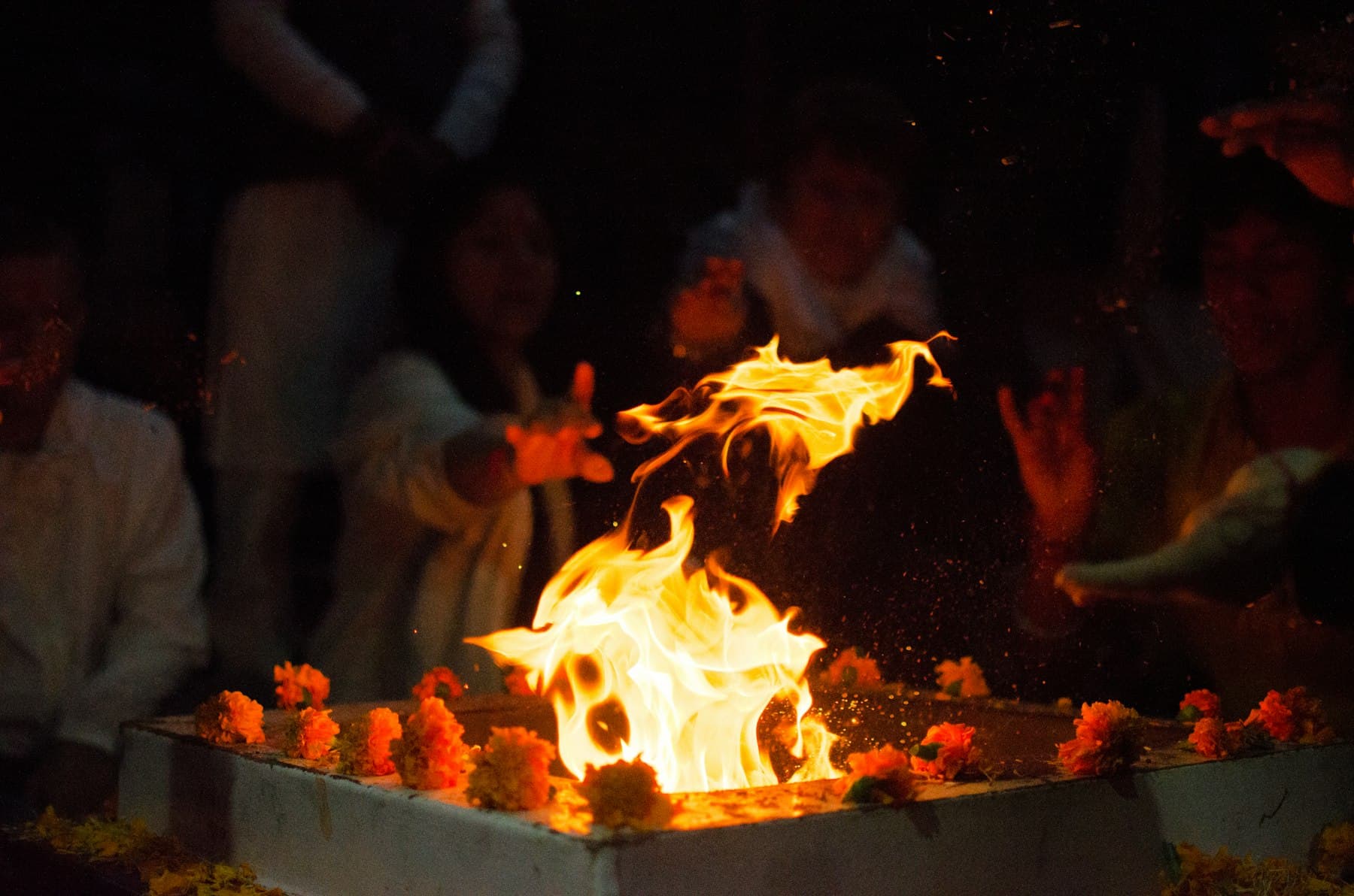The havan fire burning inside a ring of marigolds after dark