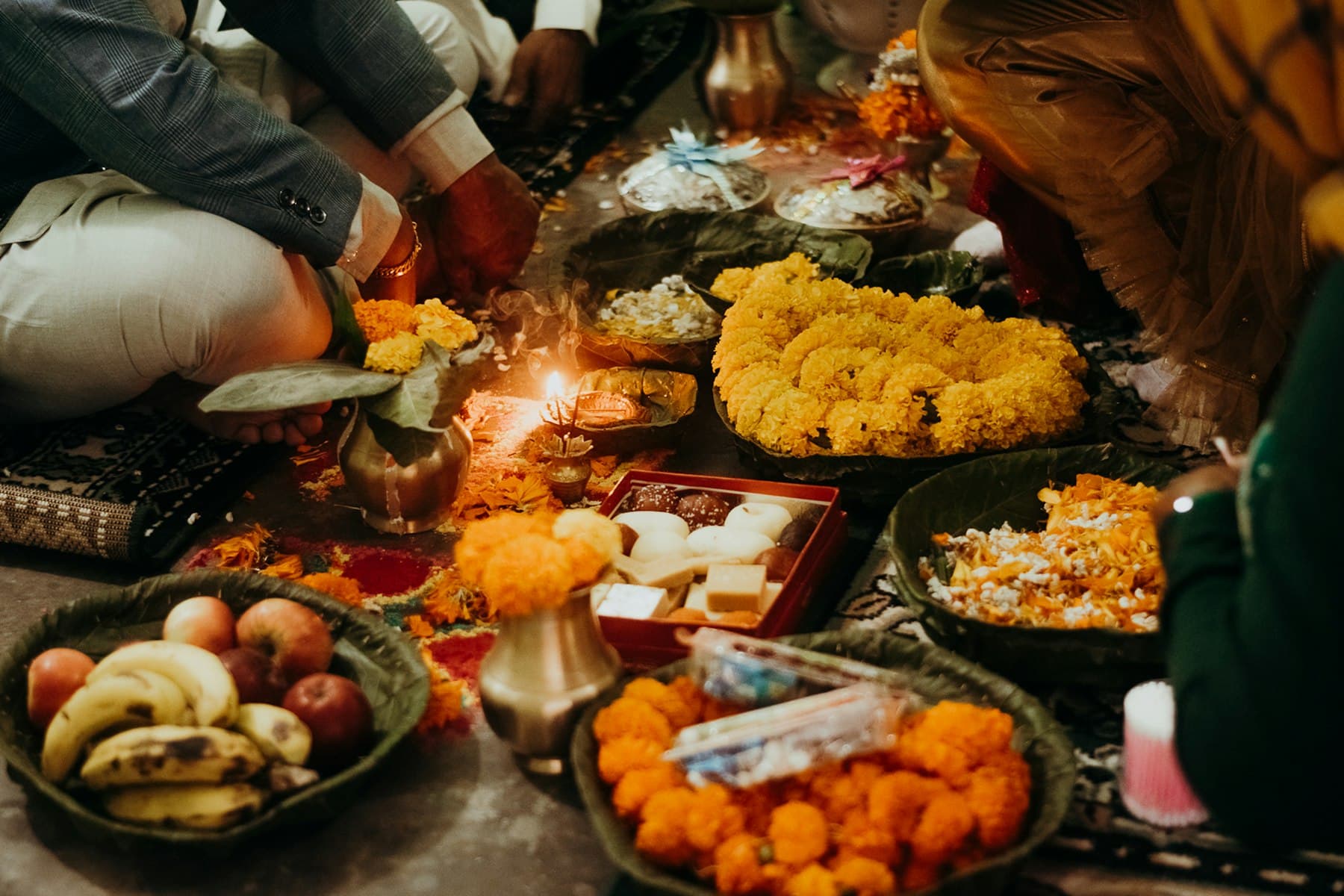Thalis of offerings, sweets and marigolds laid out on the ground for the rite