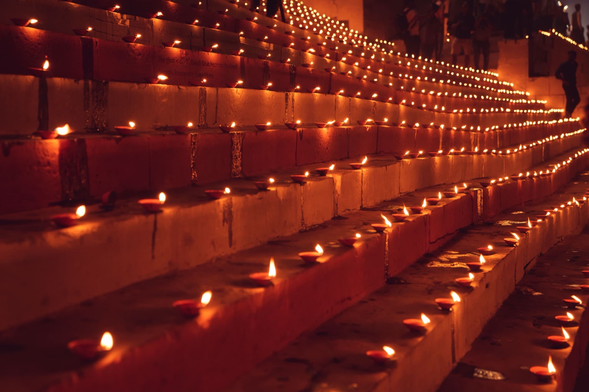 Rows of lit diyas running the length of the ghat steps after dark